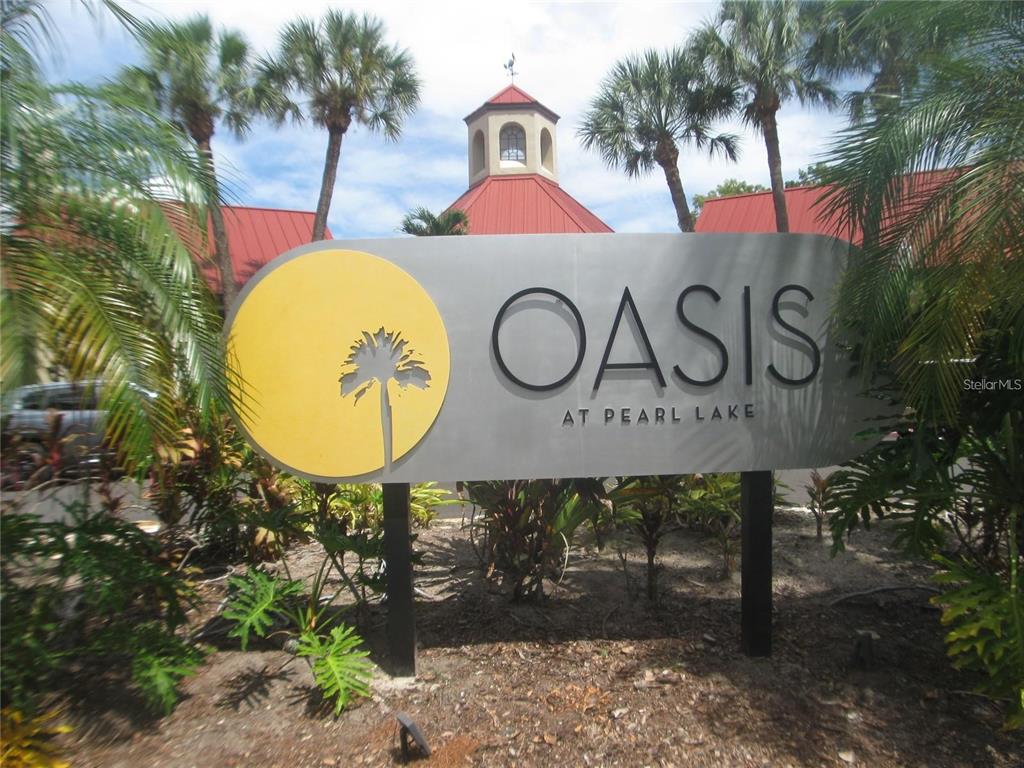 A sign for Oasis at Pearl Lake stands in front of palm trees and buildings — 199 AFTON SQUARE UNIT 210, ALTAMONTE SPRINGS, FL