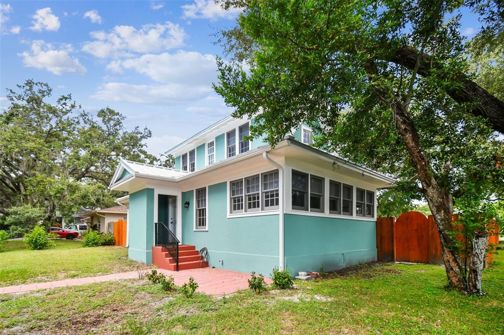 A teal two-story house with a metal roof, white trim, and red concrete steps — 758 WOOD STREET, DUNEDIN, FL