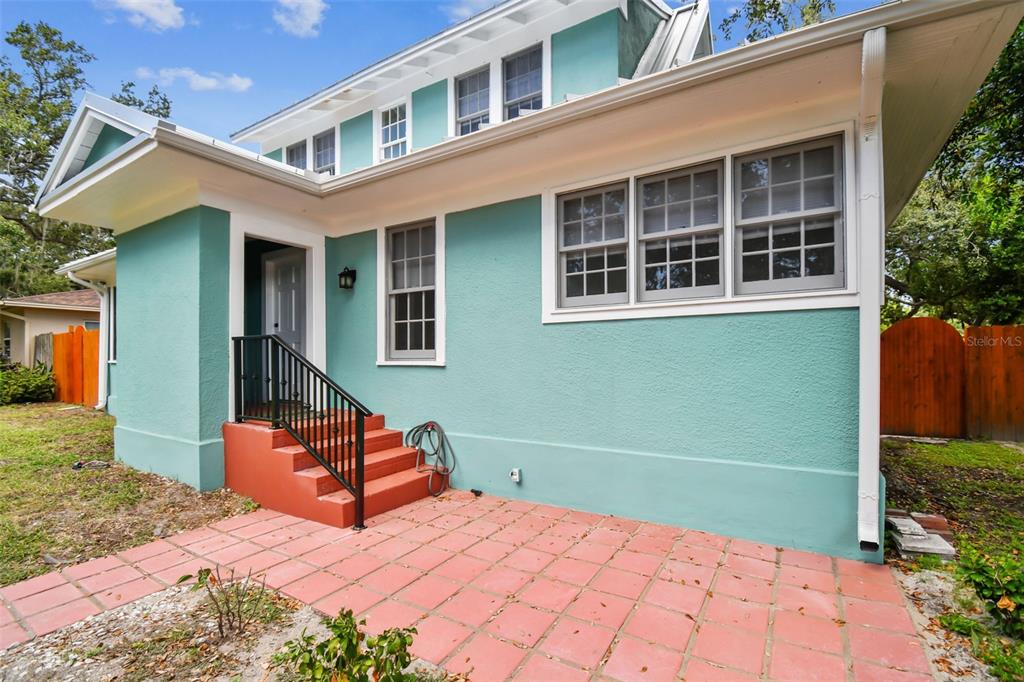 A teal house exterior features a red-tiled patio, matching red steps, and white-trimmed windows — 758 WOOD STREET, DUNEDIN, FL