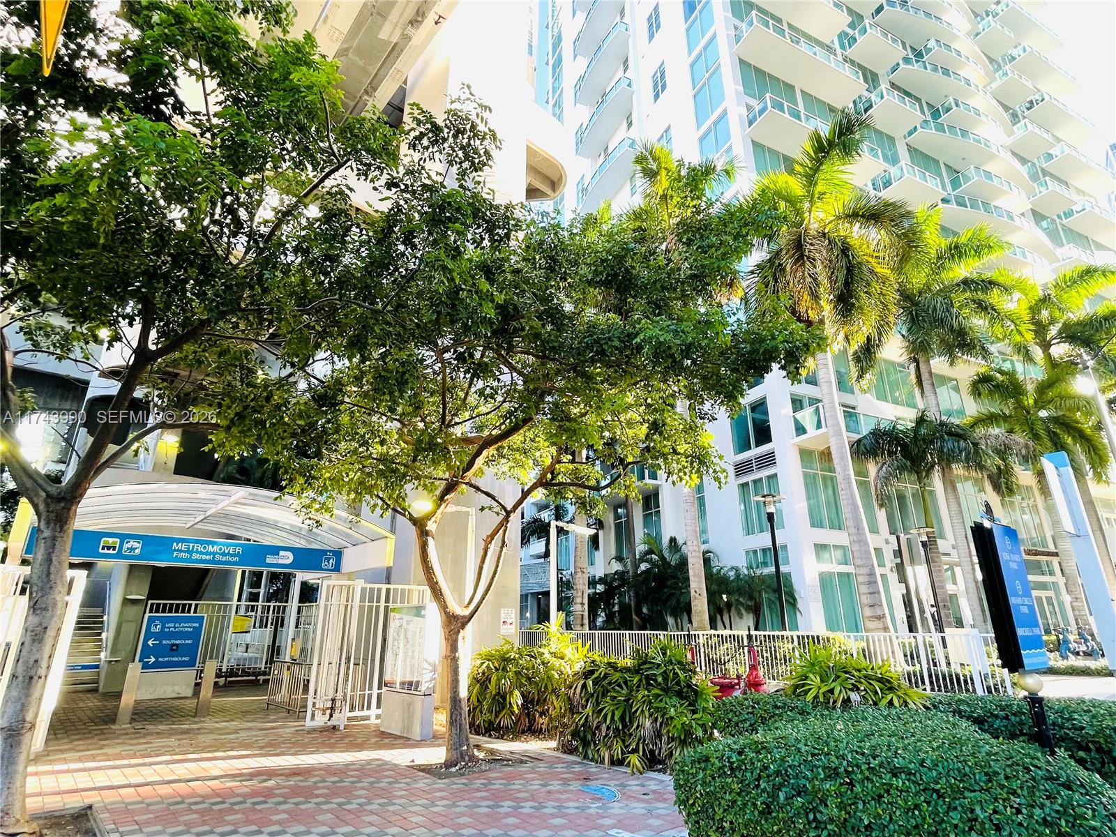 An outdoor view of the Fifth Street Metromover station entrance with surrounding trees and high-rise buildings — 41 SE 5th St # 808, Miami FL 33131, MIAMI, FL