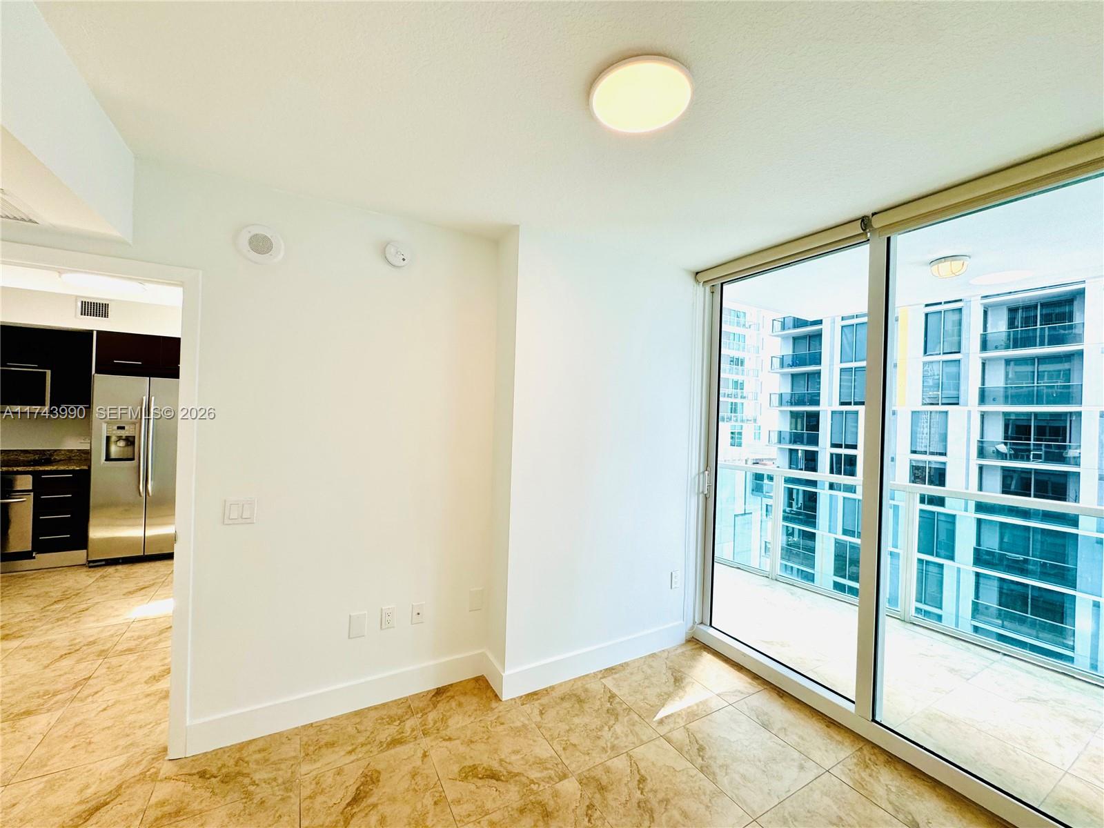 An interior room features tile flooring, white walls, and a sliding glass door to a balcony — 41 SE 5th St # 808, Miami FL 33131, MIAMI, FL