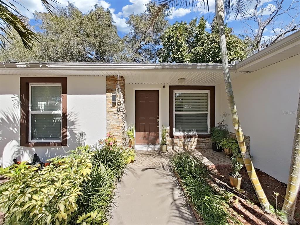The exterior of a house features a brown front door, stone accents, and landscaping — 3306 E CHELSEA STREET, TAMPA, FL