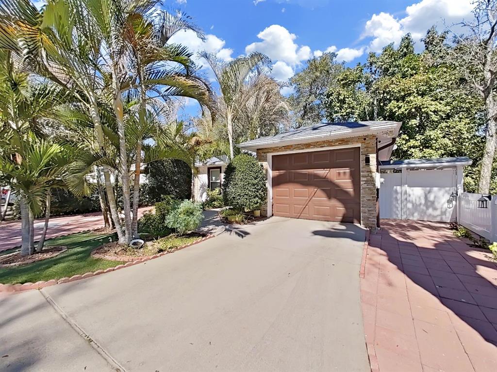 A concrete driveway leads to a single-car garage with a brown door and stone facade — 3306 E CHELSEA STREET, TAMPA, FL