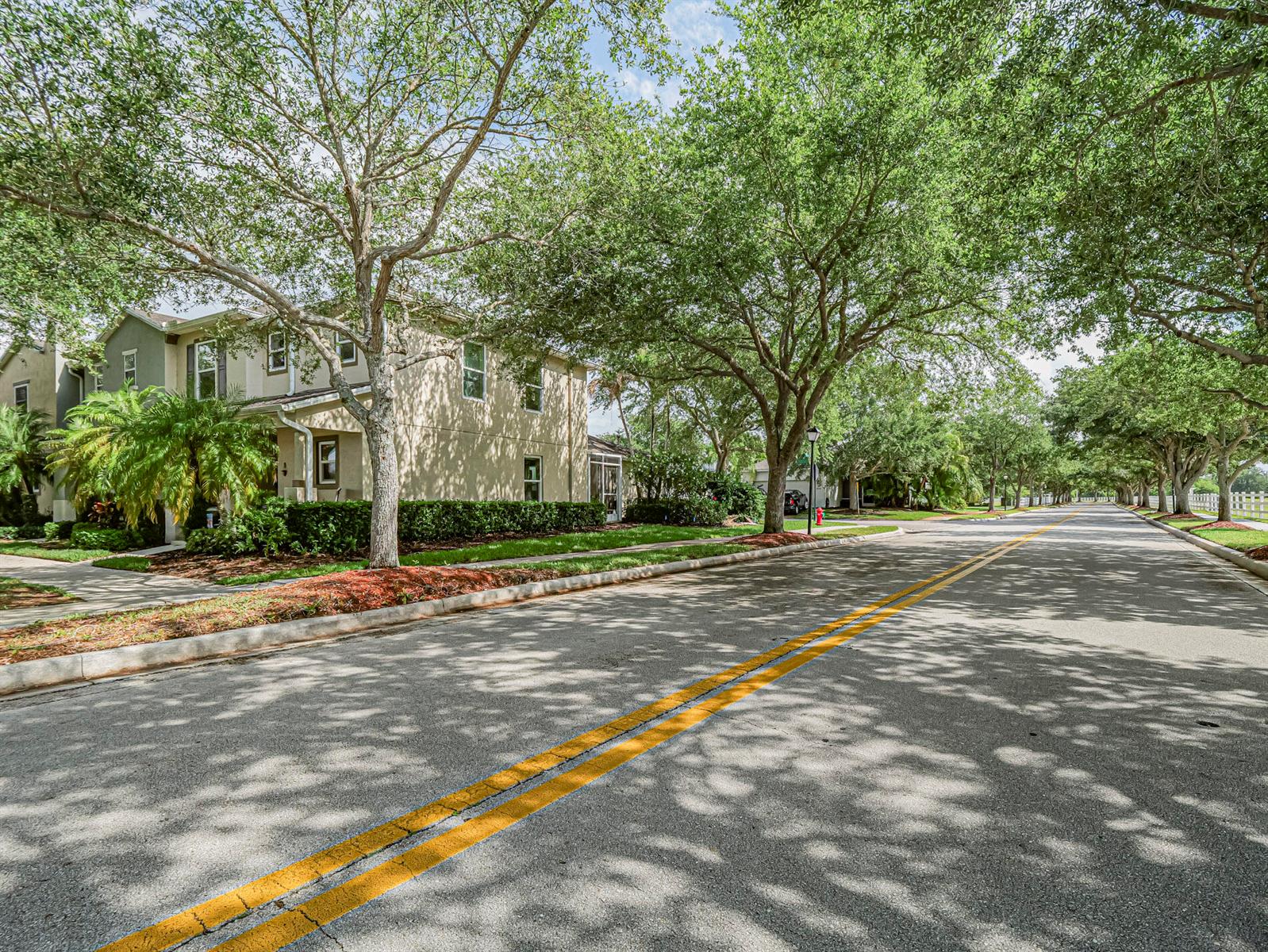 A two-story residential building sits beside a tree-lined street with yellow center lines — 1838 Pointe West Way, Vero Beach FL 32966, VERO BEACH, FL
