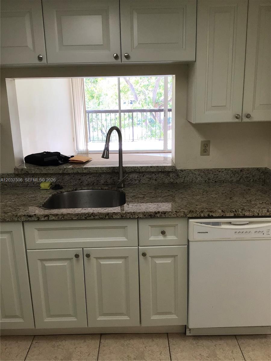 A kitchen sink with a gooseneck faucet sits below a pass-through window with granite countertops — 10975 SW 107th St # 302, Miami FL 33176, MIAMI, FL