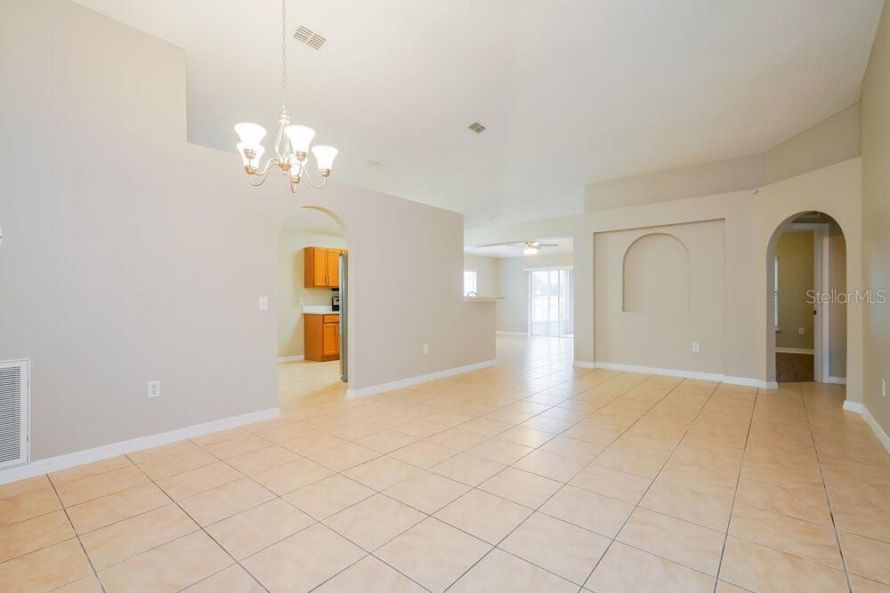 An open-concept living area features beige walls, tile flooring, and an arched entryway to the kitchen — 2338 ANDREWS VALLEY DRIVE, KISSIMMEE, FL