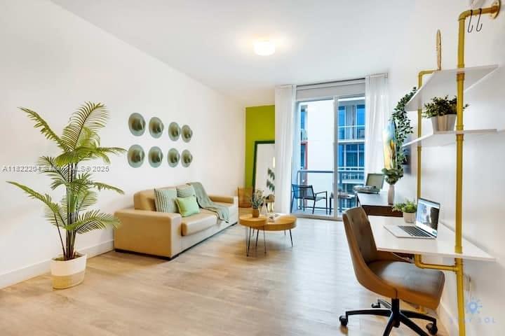 A modern living room features a beige sofa, a desk with shelving, and a balcony view — 777 N Ocean Dr # N521, Hollywood FL 33019, HOLLYWOOD, FL