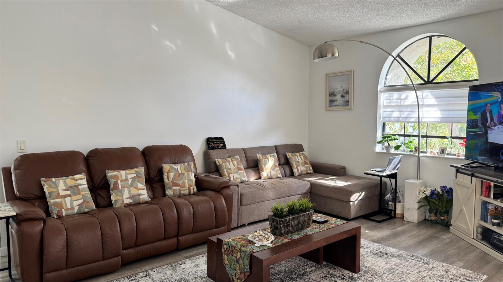 A living room features a brown leather sofa, a gray sectional, and an arched window — 5267 Europa Drive, Boynton Beach FL 33437, BOYNTON BEACH, FL