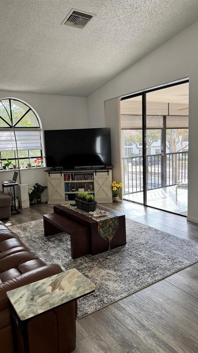 A living room features a large television, a wooden coffee table, and a sliding glass door — 5267 Europa Drive, Boynton Beach FL 33437, BOYNTON BEACH, FL