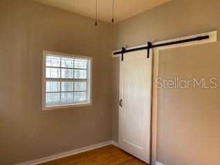 A room with light-colored walls, a window with security bars, and a white sliding barn door — 912 E SAINT CLAIR STREET, TAMPA, FL