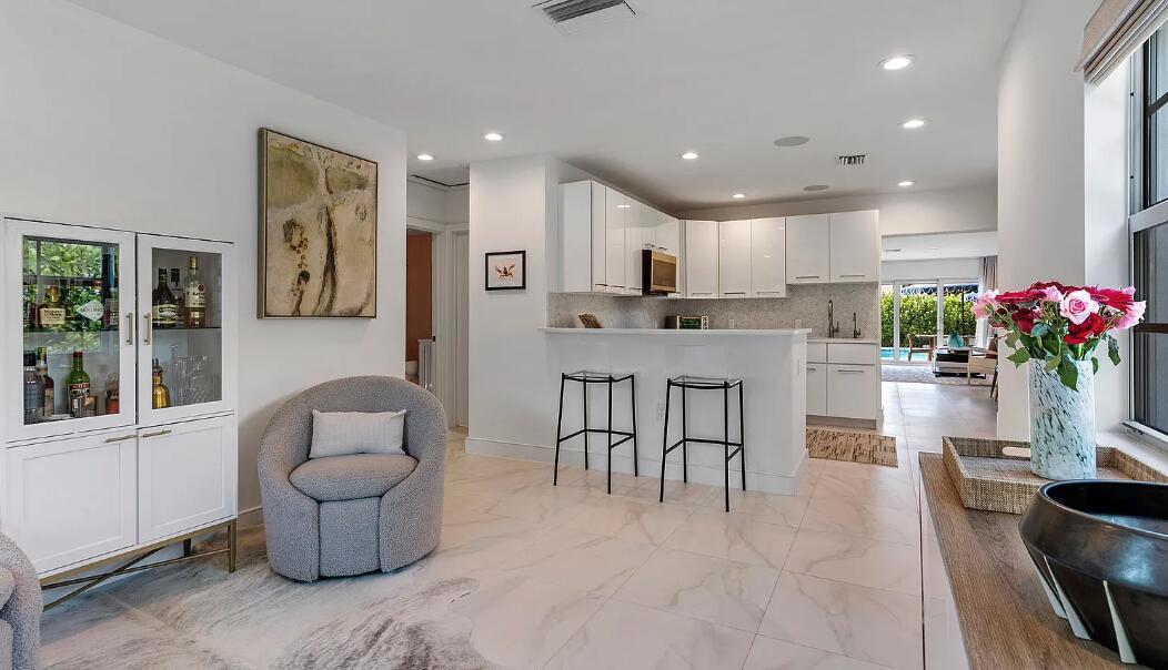 A modern kitchen with white cabinets and a breakfast bar overlooks a living area — 406 35th Street, West Palm Beach FL 33407, WEST PALM BEACH, FL