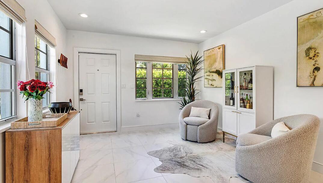 A bright entryway features white tile floors, two textured armchairs, a bar cabinet, and windows — 406 35th Street, West Palm Beach FL 33407, WEST PALM BEACH, FL