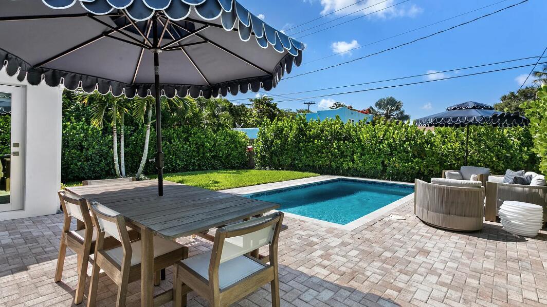 A patio with a dining set, pool, and lounge chairs under umbrellas in a backyard — 406 35th Street, West Palm Beach FL 33407, WEST PALM BEACH, FL