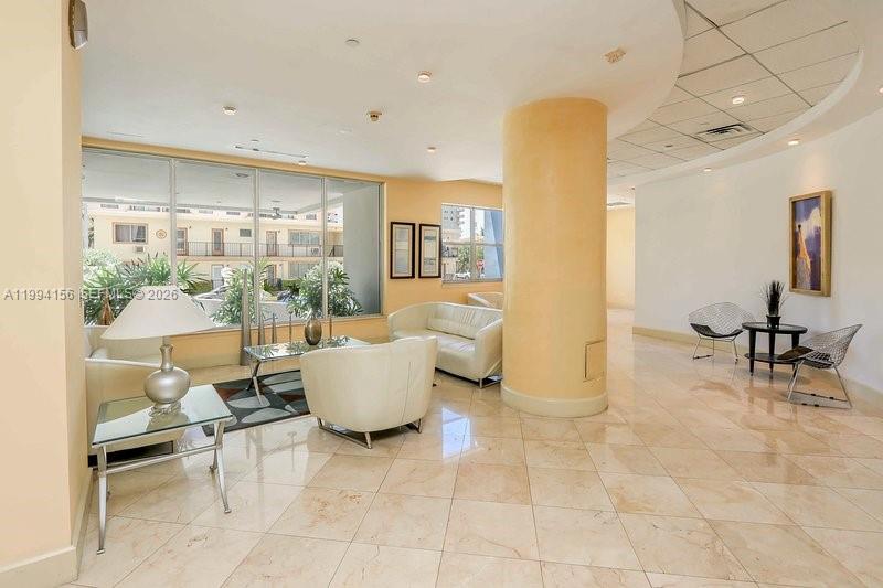A bright lobby features a large central column, cream-colored seating, and polished tile floors — 401 69th St # 505, Miami Beach FL 33141, MIAMI BEACH, FL
