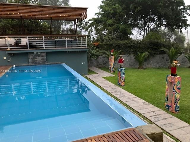 An outdoor swimming pool sits beside a grassy lawn with decorative pedestals and a deck — 130 Av. Malecon, California, Chosica, Lima - Peru, FL, FL