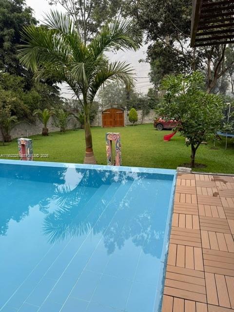 A swimming pool sits in front of a grassy yard with trees and a wooden gate — 130 Av. Malecon, California, Chosica, Lima - Peru, FL, FL