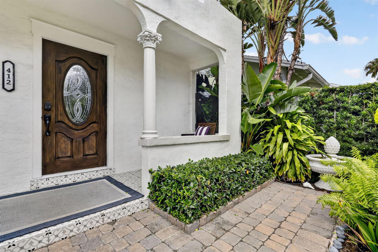 A white stucco house entrance features a wooden door, a decorative column, and tiled steps — 412 El Prado, West Palm Beach FL 33405, WEST PALM BEACH, FL
