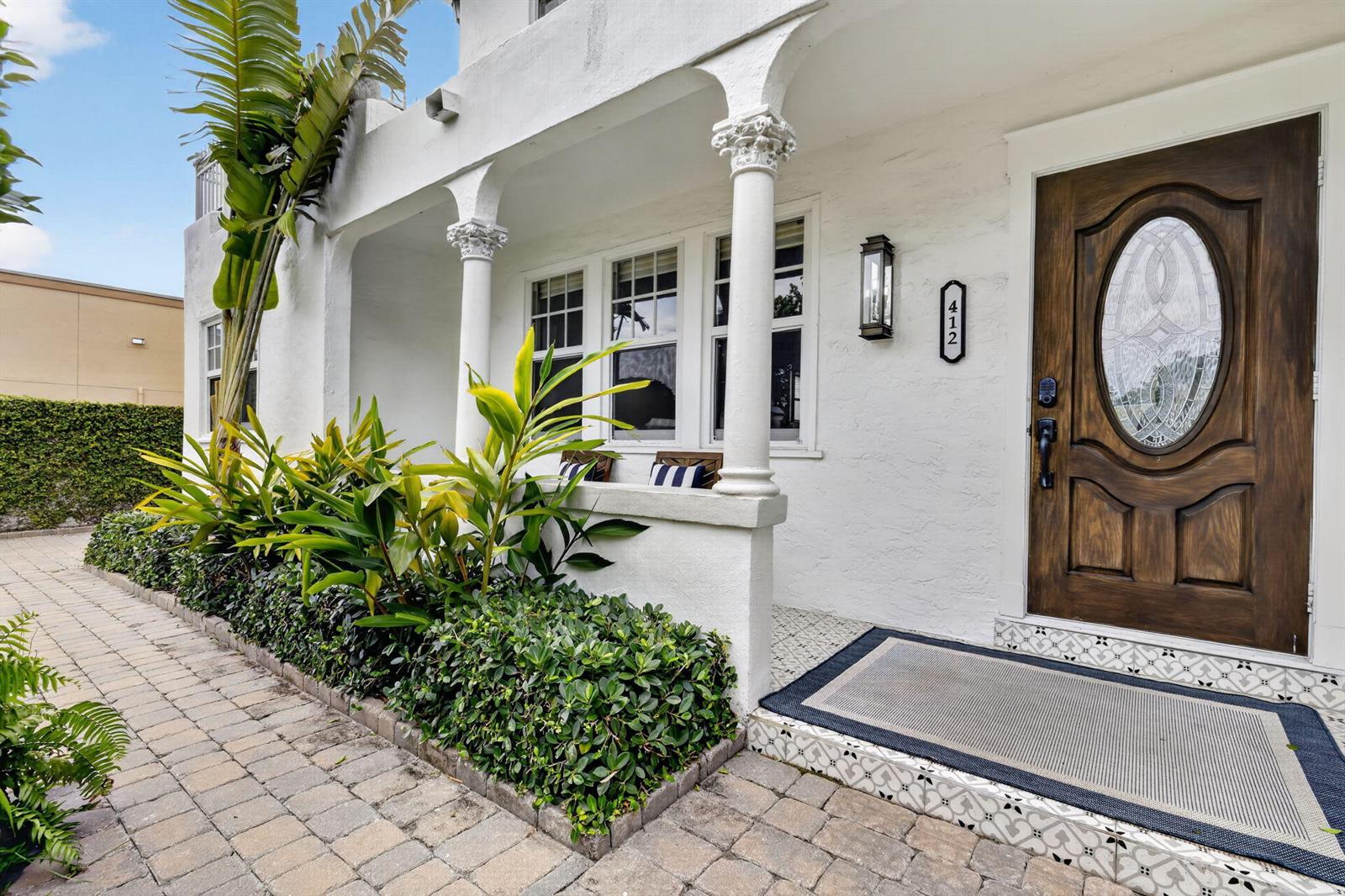 A white house exterior features a covered porch with decorative columns and a wooden door — 412 El Prado, West Palm Beach FL 33405, WEST PALM BEACH, FL