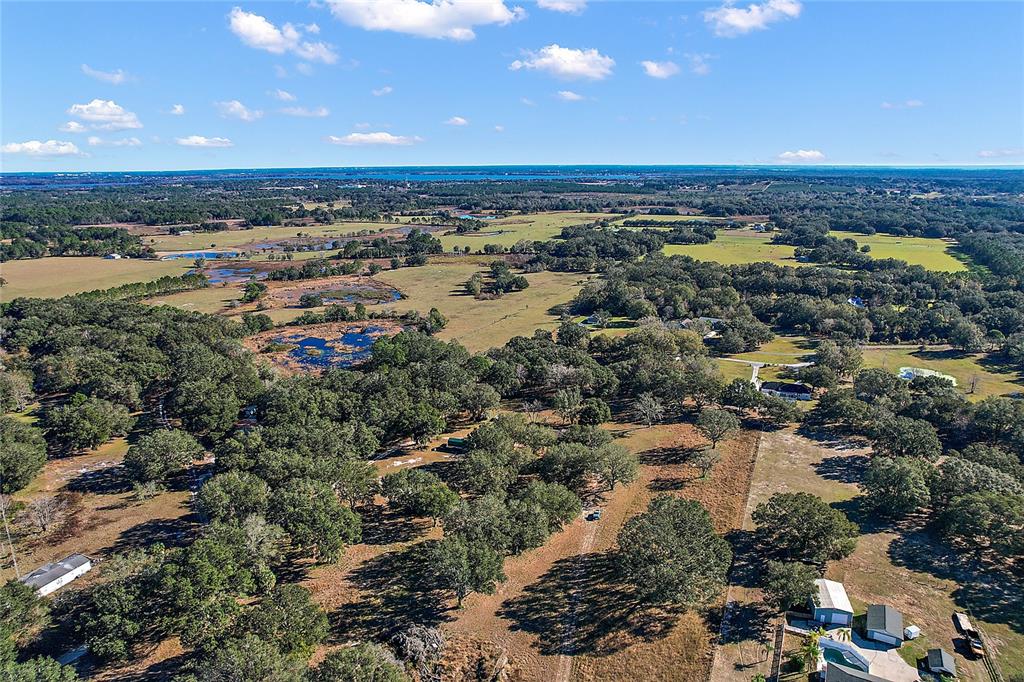 An aerial view shows a large rural property with wooded areas, open fields, and ponds — 0000 SILVERWOOD LANE, HOWEY IN THE HILLS, FL