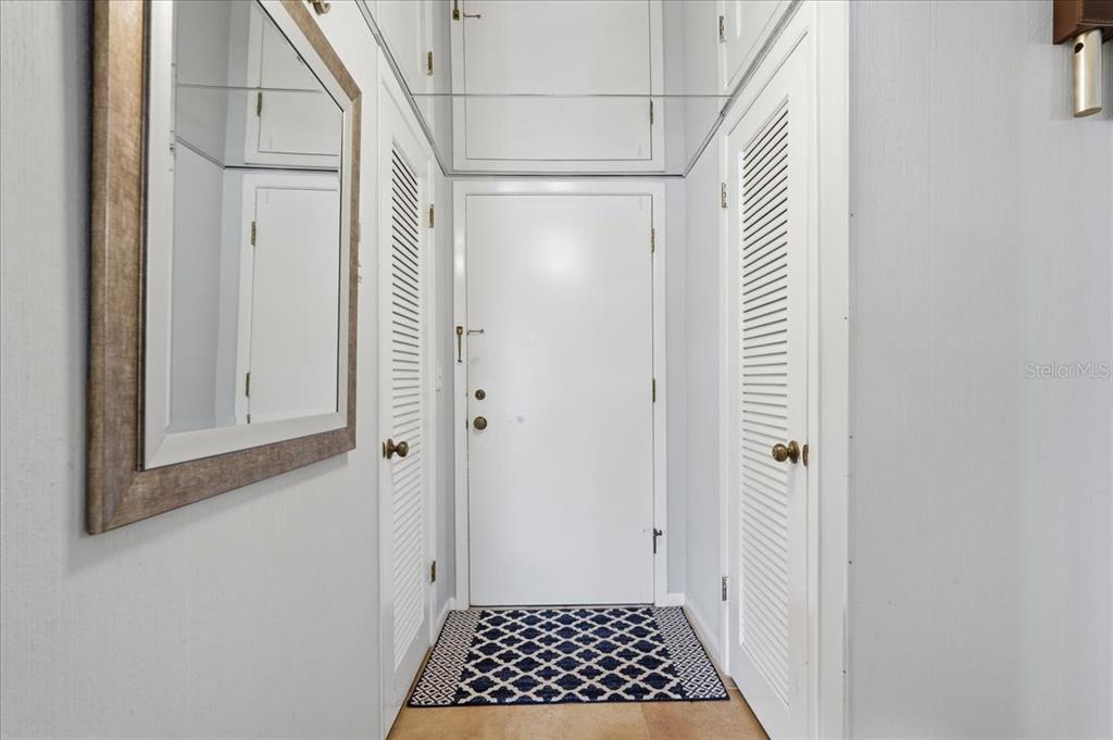 A hallway features patterned carpet, yellow walls, framed artwork, and two white elevator doors — 5396 GULF BOULEVARD UNIT 304, ST PETE BEACH, FL