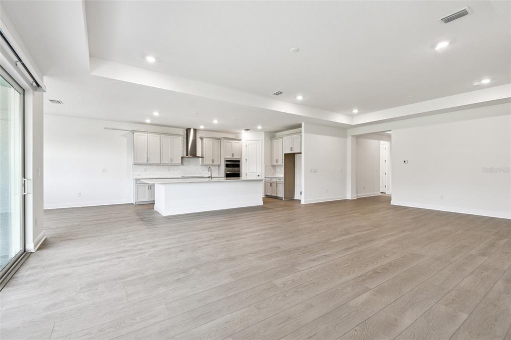 An open-concept kitchen features light gray cabinetry, a central island, and wood-look flooring — 3673 3673 142ND TER E, PARRISH, FL