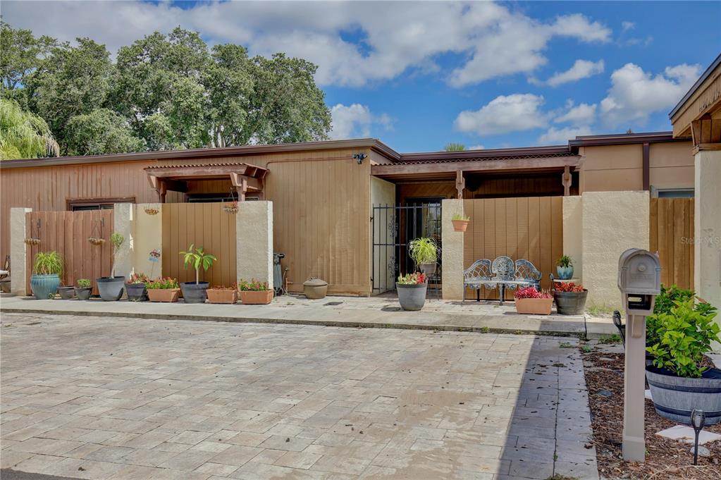 A paved driveway leads to the front entrances of a single-story home with wooden siding — 2339 INAGUA WAY, WINTER PARK, FL