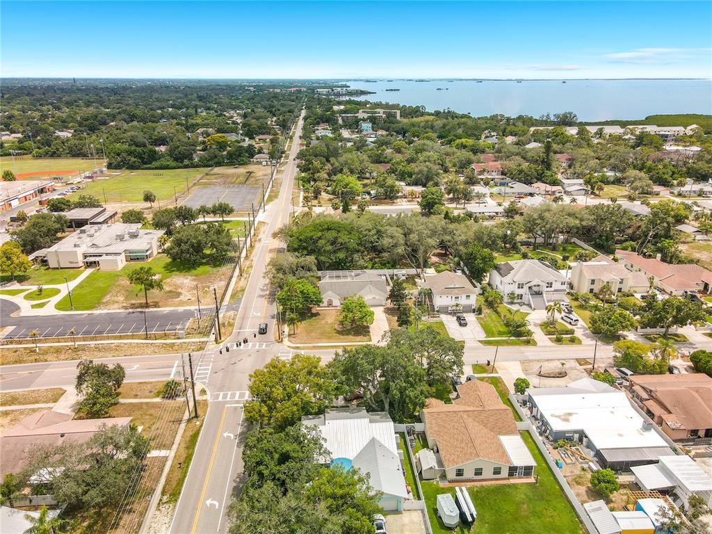 An aerial view shows a suburban neighborhood with houses, trees, and a road leading toward water — 1601 GULF ROAD, TARPON SPRINGS, FL