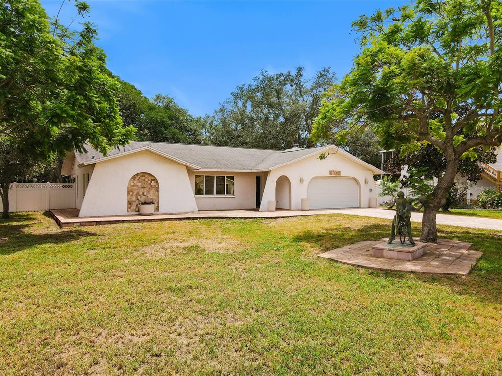 A single-story house with a white stucco facade, arched entryway, and a front lawn statue — 1601 GULF ROAD, TARPON SPRINGS, FL