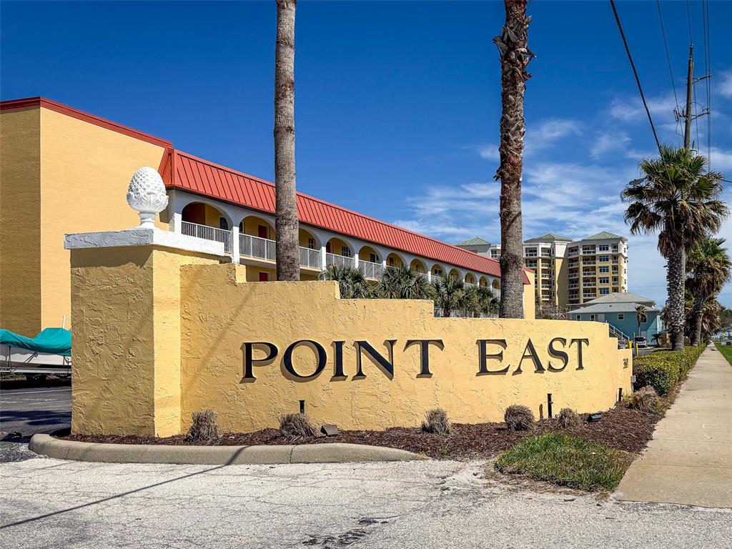 A yellow stucco sign with the text Point East stands before a multi-story building — 3801 S ATLANTIC AVENUE UNIT 316, NEW SMYRNA BEACH, FL