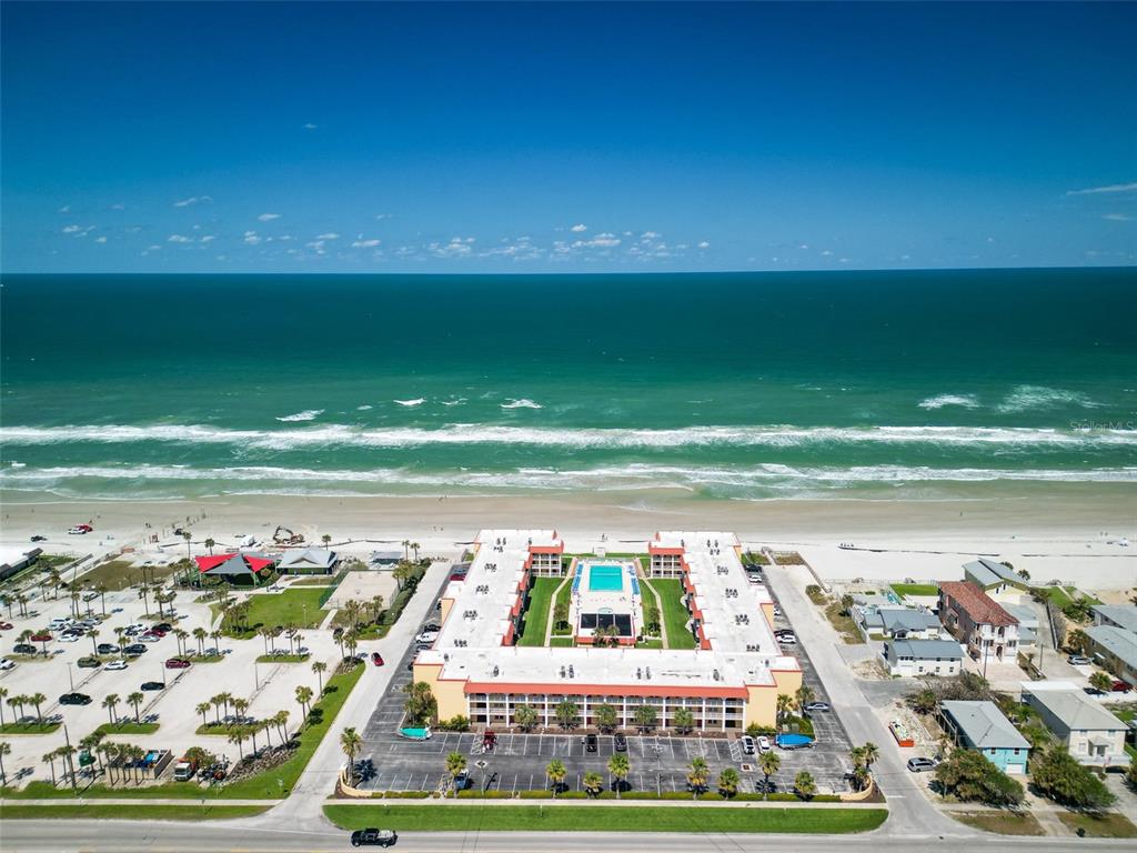 An aerial view shows a U-shaped beachfront resort building with a central pool and parking — 3801 S ATLANTIC AVENUE UNIT 316, NEW SMYRNA BEACH, FL