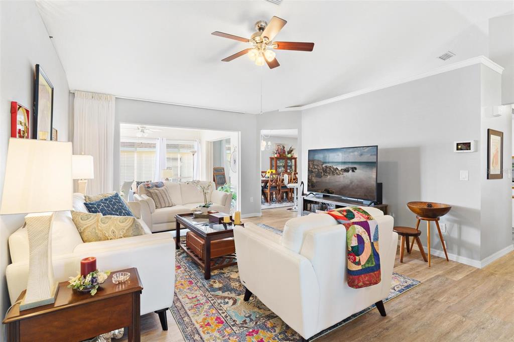 A bright living room features white furniture, a colorful area rug, and a ceiling fan — 17209 SE 115TH TERRACE ROAD, SUMMERFIELD, FL