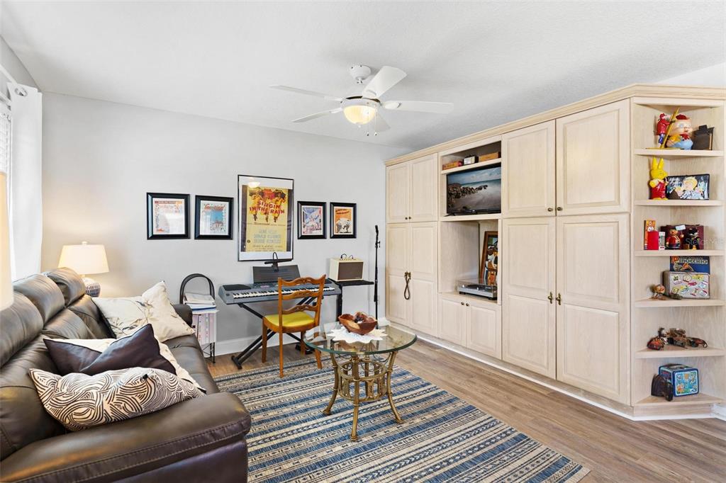 A living room features a dark leather sofa, a keyboard, and a large built-in wooden cabinet — 17209 SE 115TH TERRACE ROAD, SUMMERFIELD, FL