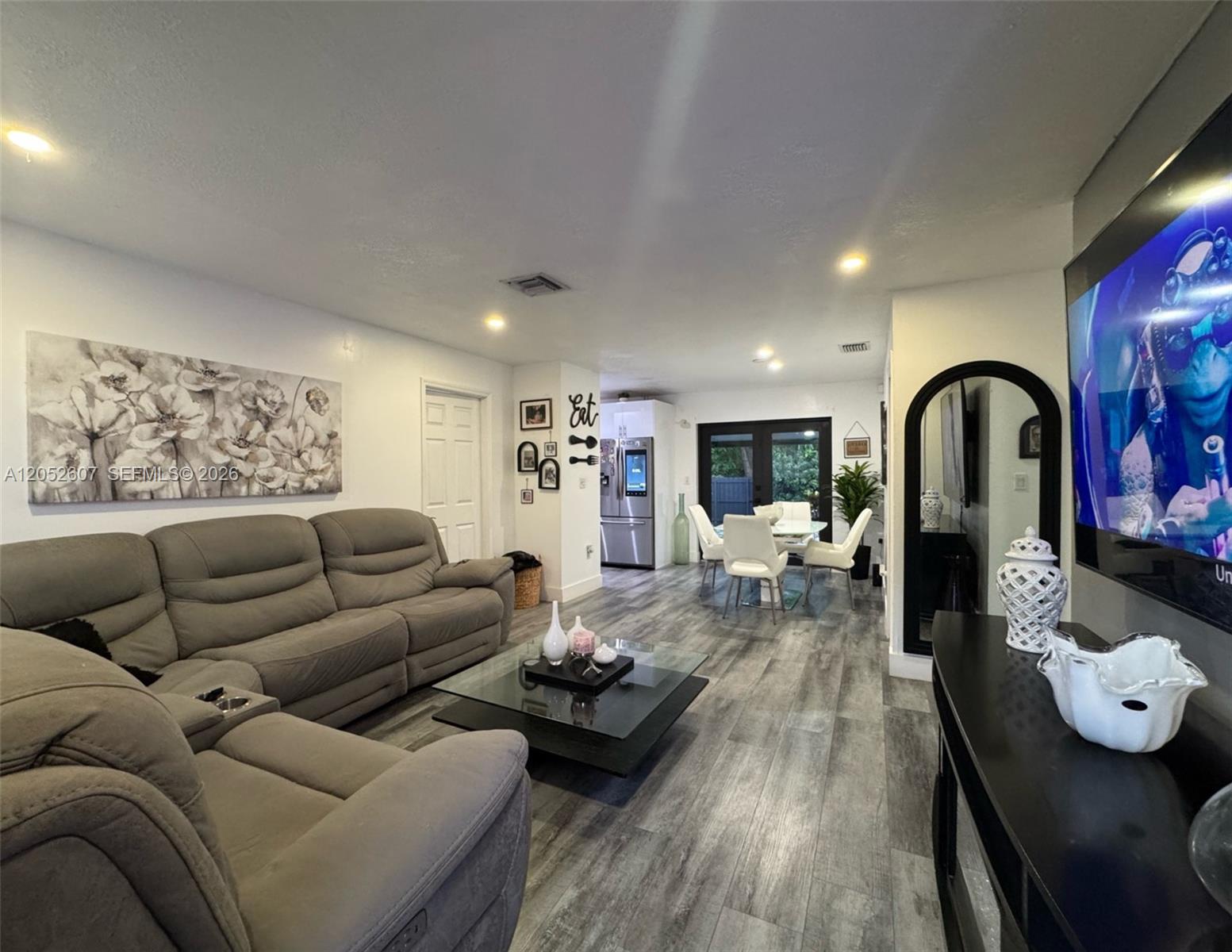 A living room and dining area feature gray wood-look flooring and a large sectional sofa — 10660 SW 164th St, Miami FL 33157, MIAMI, FL