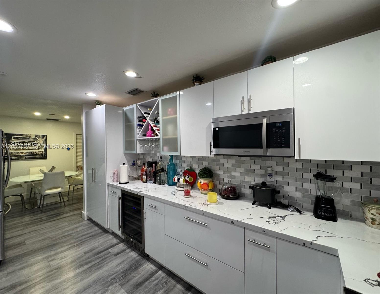 A modern kitchen features white glossy cabinets, marble-patterned countertops, and a stainless steel microwave — 10660 SW 164th St, Miami FL 33157, MIAMI, FL