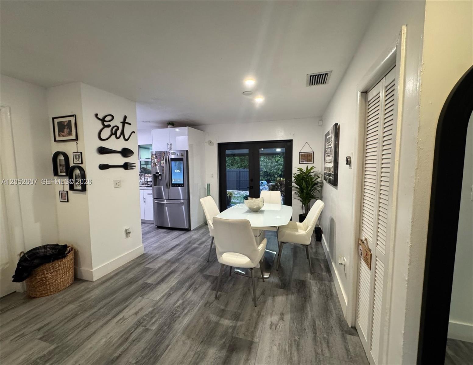 A dining area features a white table, four chairs, and wood-look flooring near a kitchen — 10660 SW 164th St, Miami FL 33157, MIAMI, FL