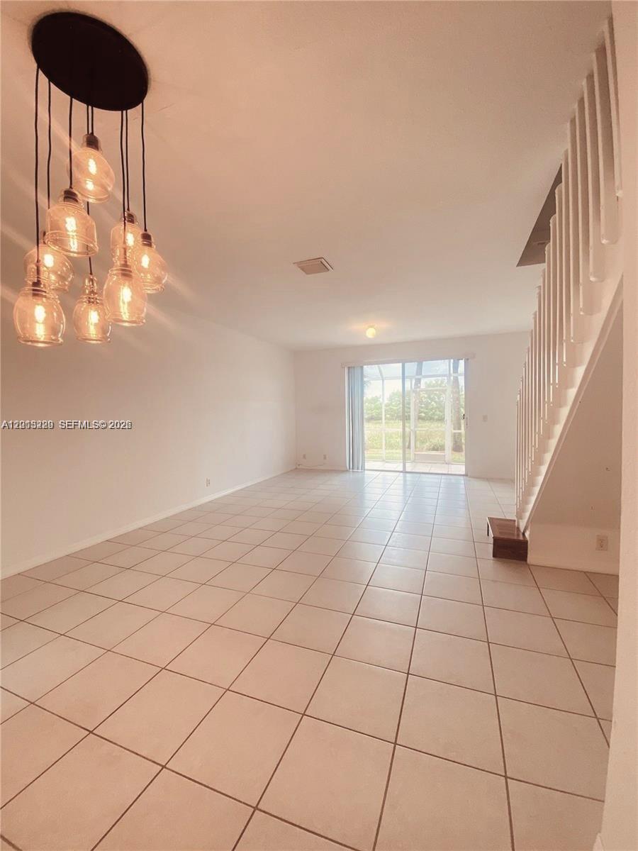 An open living area features white tile flooring, a modern pendant light fixture, and stairs — 2567 Cordoba Bnd, Weston FL 33327, WESTON, FL