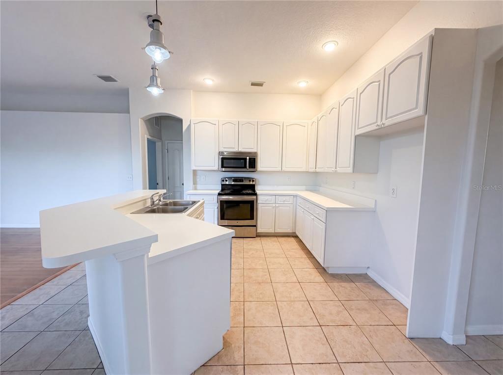 A kitchen features white cabinets, stainless steel appliances, a breakfast bar, and tiled flooring — 203 TAYLOR BAY LANE, BRANDON, FL