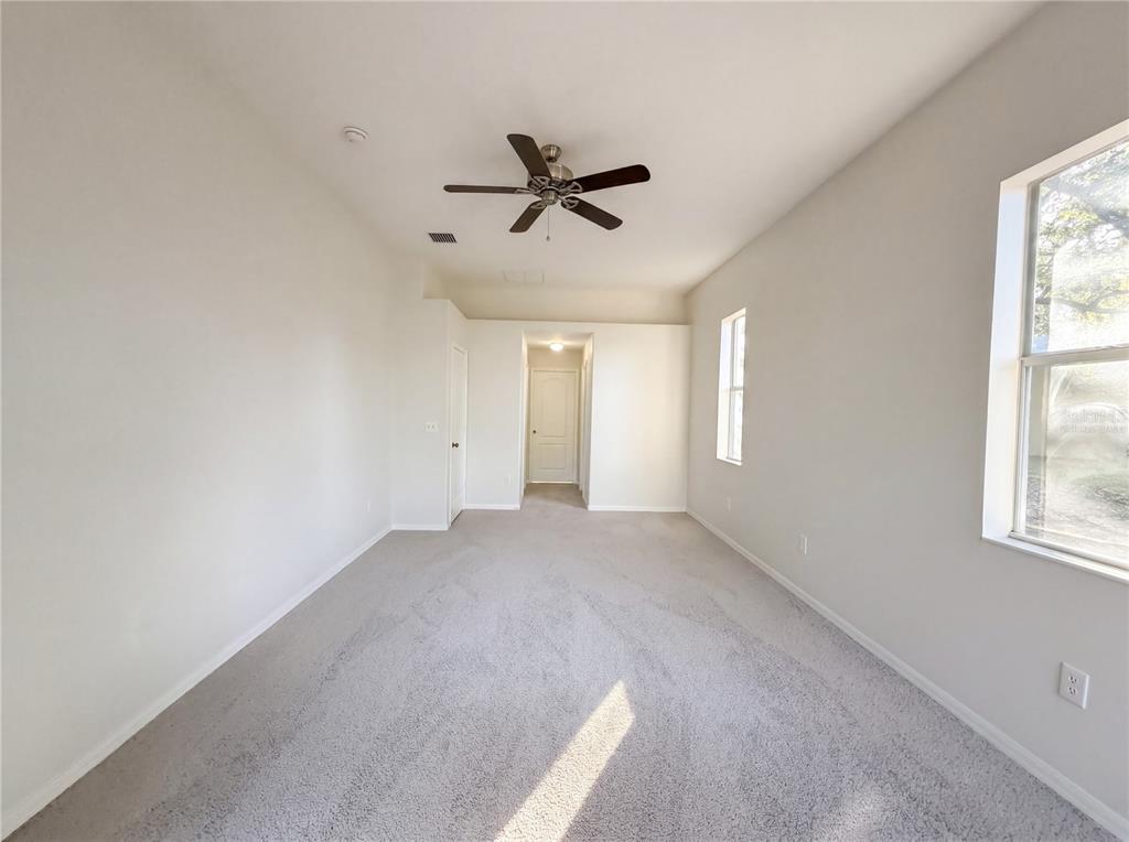 An empty room with gray carpet, white walls, a ceiling fan, and two windows — 203 TAYLOR BAY LANE, BRANDON, FL
