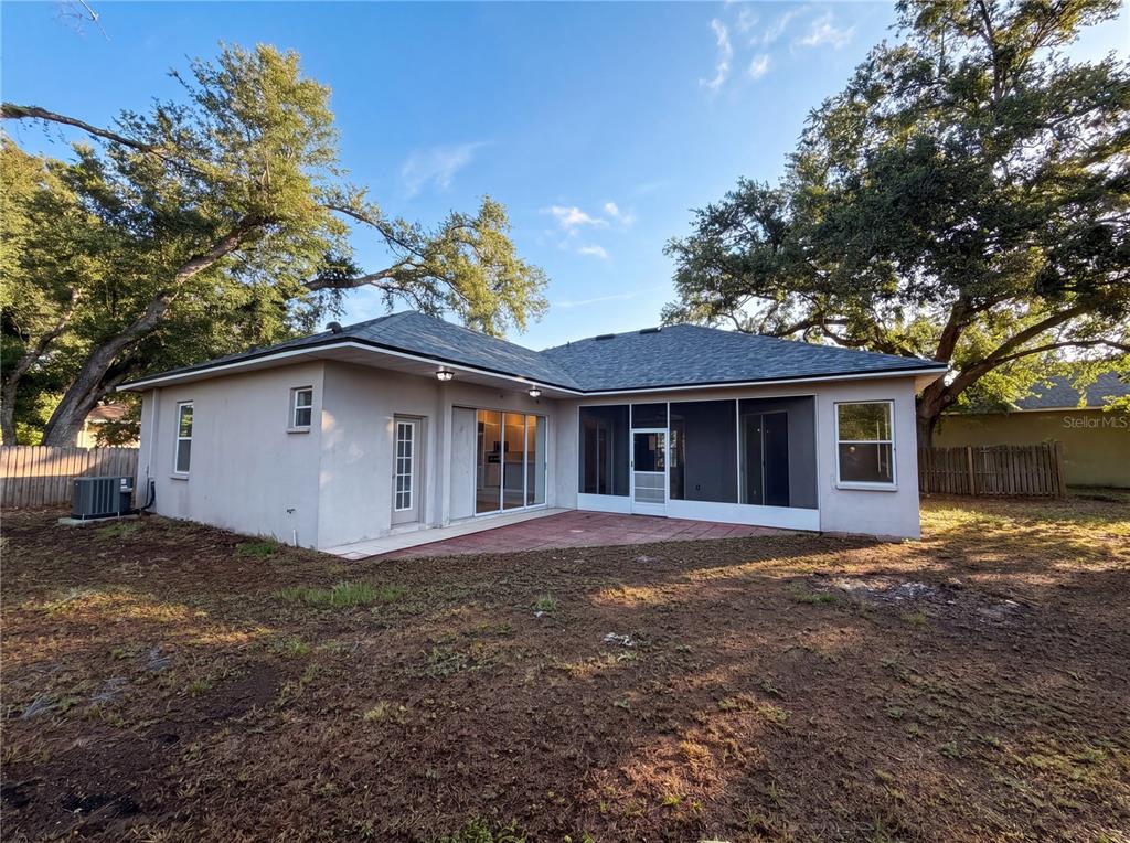 The exterior rear view of a single-story house features a screened patio and yard — 203 TAYLOR BAY LANE, BRANDON, FL