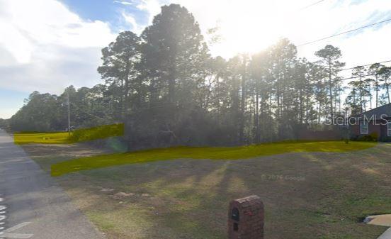 A vacant, grassy lot with trees is highlighted in yellow next to a brick house — 2249 WINFIELD DRIVE, NAVARRE, FL