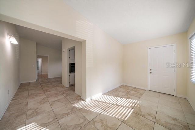 An interior view shows a tiled room with a white door and an open doorway — 533 YELVINGTON AVENUE, CLEARWATER, FL