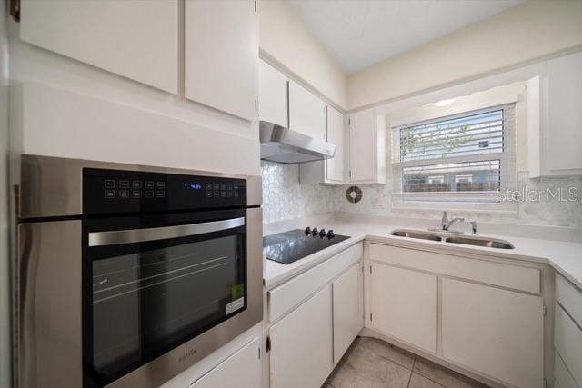 A kitchen features white cabinets, a stainless steel wall oven, and a window above the sink — 533 YELVINGTON AVENUE, CLEARWATER, FL