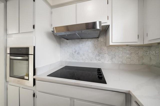 A kitchen features white cabinets, a stainless steel range hood, and a black glass cooktop — 533 YELVINGTON AVENUE, CLEARWATER, FL