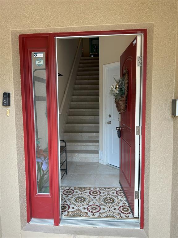 An open red front door reveals an entryway with a staircase and tiled flooring — 844 CALLISTA CAY LOOP, TARPON SPRINGS, FL