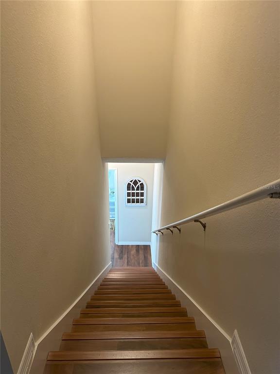 A view looking down a wooden staircase toward a hallway with a decorative arched window — 844 CALLISTA CAY LOOP, TARPON SPRINGS, FL