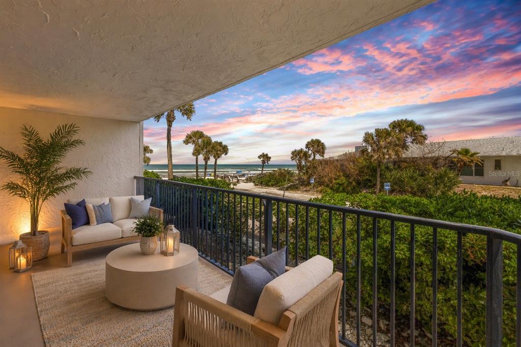 A balcony with outdoor seating overlooks a beach and ocean at sunset — 3001 S ATLANTIC AVENUE UNIT 503, NEW SMYRNA BEACH, FL