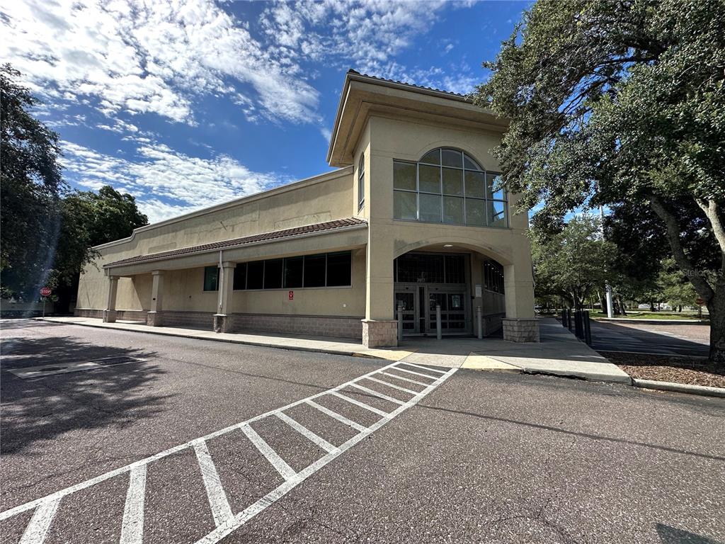 A beige commercial building with a covered entrance and large windows stands under a blue sky — 3917 N NEBRASKA AVENUE, TAMPA, FL