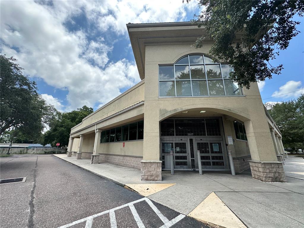 A beige commercial building with a glass-paneled entrance and arched window under a cloudy sky — 3917 N NEBRASKA AVENUE, TAMPA, FL