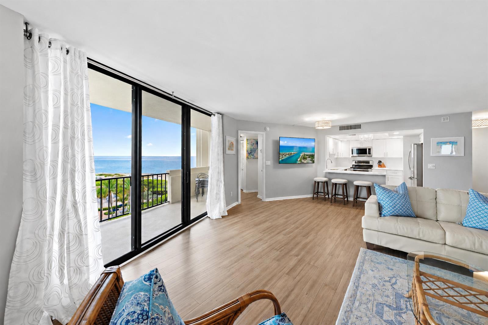 A living room with light wood floors, a white sofa, and a balcony overlooking the ocean — 2800 N Ocean Drive # 7c, Singer Island FL 33404, SINGER ISLAND, FL