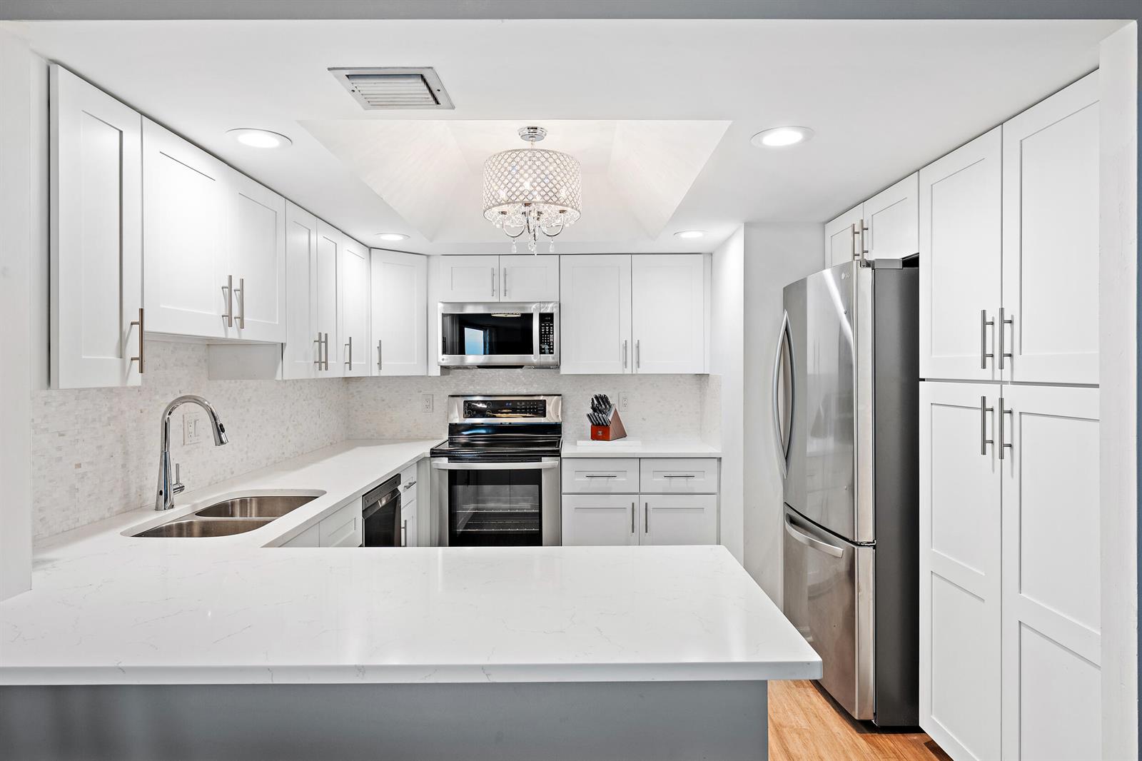 A modern kitchen features white cabinetry, stainless steel appliances, and a white quartz countertop — 2800 N Ocean Drive # 7c, Singer Island FL 33404, SINGER ISLAND, FL